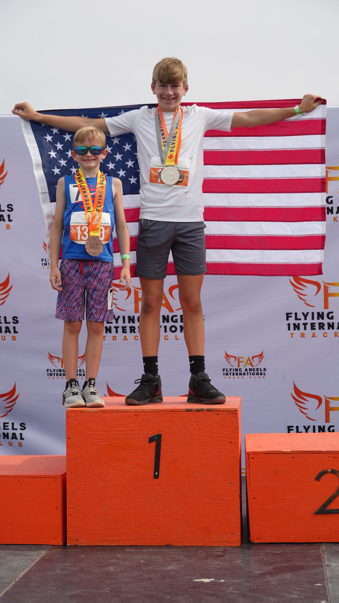 Two young athletes on the podium holding the USA flag